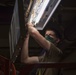 USS America (LHA 6) Sailor Inspects Lighting Equipment