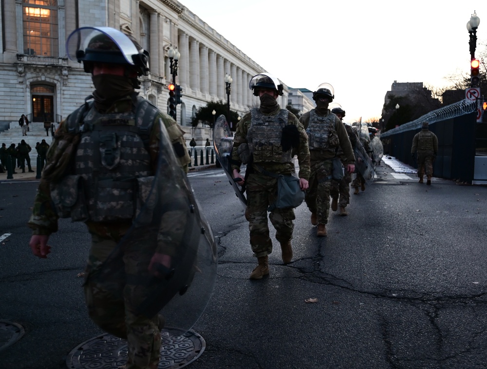 National Guard solider march down street in riot gear