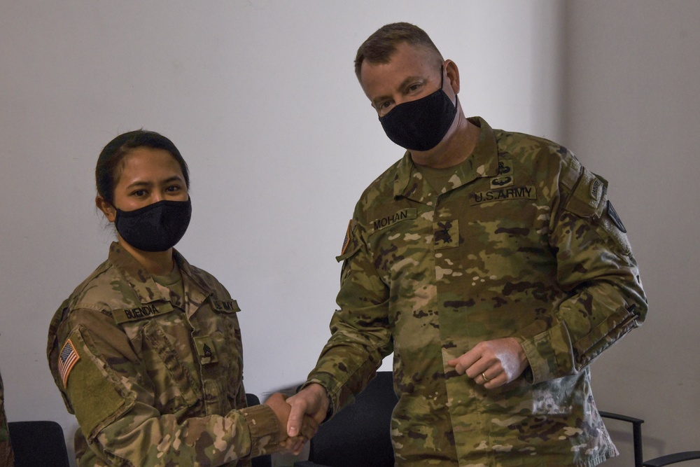 U.S. Army Maj. General Christopher Mohann presents his coin to Alaska Army National Guard Staff Sgt. Jennessymae Buendia