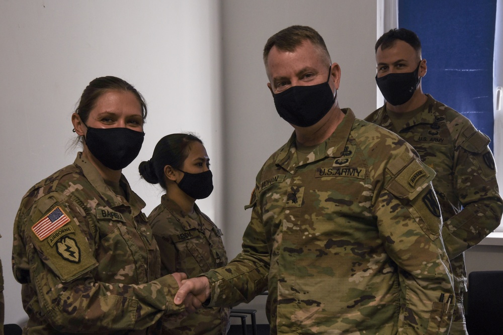 U.S. Army Maj. General Christopher Mohann presents his coin to Alaska Army National Guard Staff Sgt. Corine Barrera.