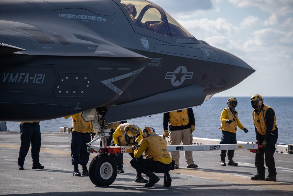 Sailors assigned to the forward-deployed amphibious assault ship USS America (LHA 6) prepare to tow an F-35B Lightning II aircraft assigned to the 31st Marine Expeditionary Unit (MEU) on the ship’s flight deck