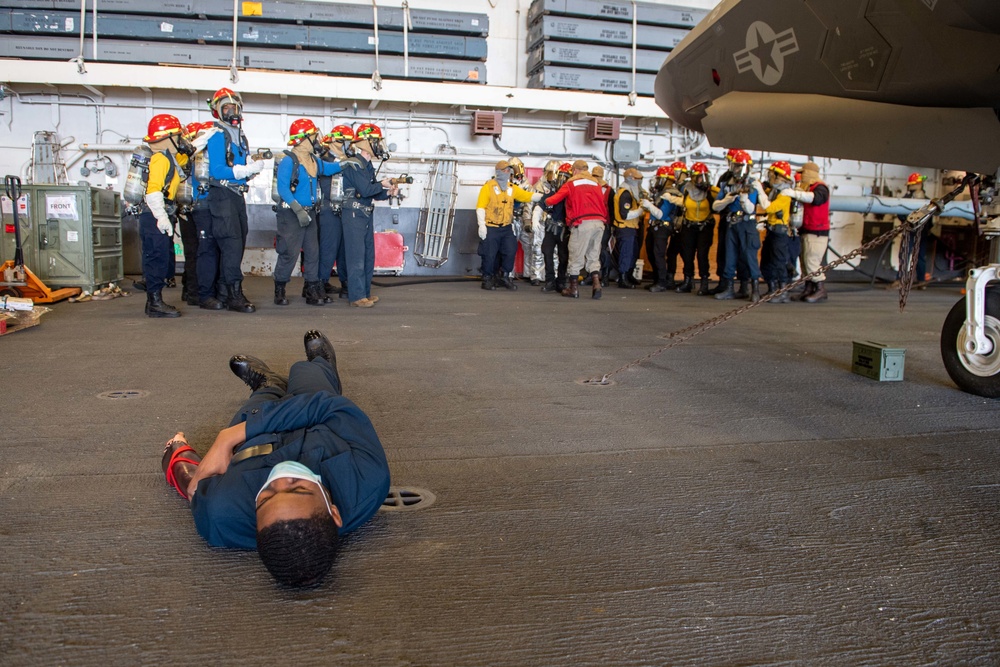 Sailors practice firefighting techniques during a general quarters drill with simulated casualties in the hangar bay of the forward-deployed amphibious assault ship USS America (LHA 6)