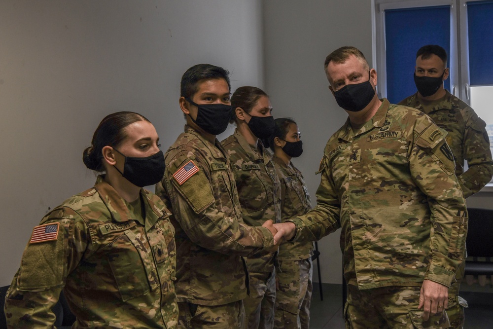 U.S. Army Maj. General Christopher Mohann presents his coin to Alaska Army National Guard Specialist Lester Tuazon for technical expertise in surveying the area needed for the new AAFES modular containerized store location