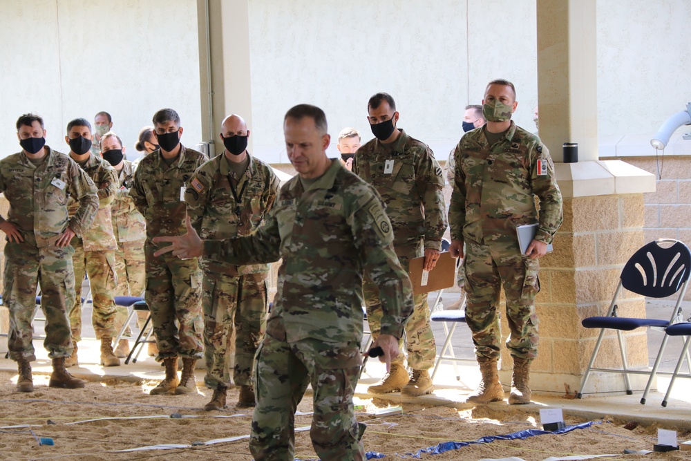 Colonel briefing at a JRTC Task Force pre 21-04-rotational while standing in an outdoor sand table.