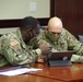 Senior enlisted leadership leaning over and talking at meeting room table during a pre-JRTC RTN 21-04 rotational brief.