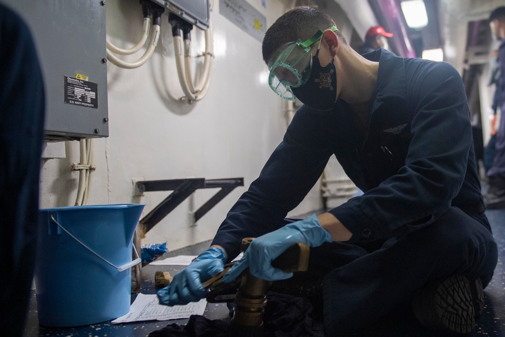 Sailor conducts routine maintenance on a fire hose.