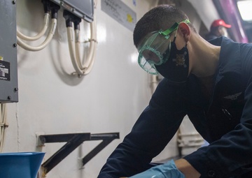 Sailor conducts routine maintenance on a fire hose.