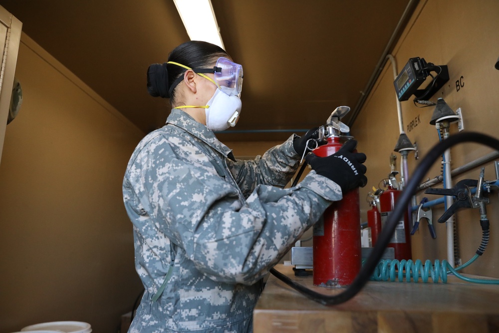 Soldier inspects a fire extinguisher.