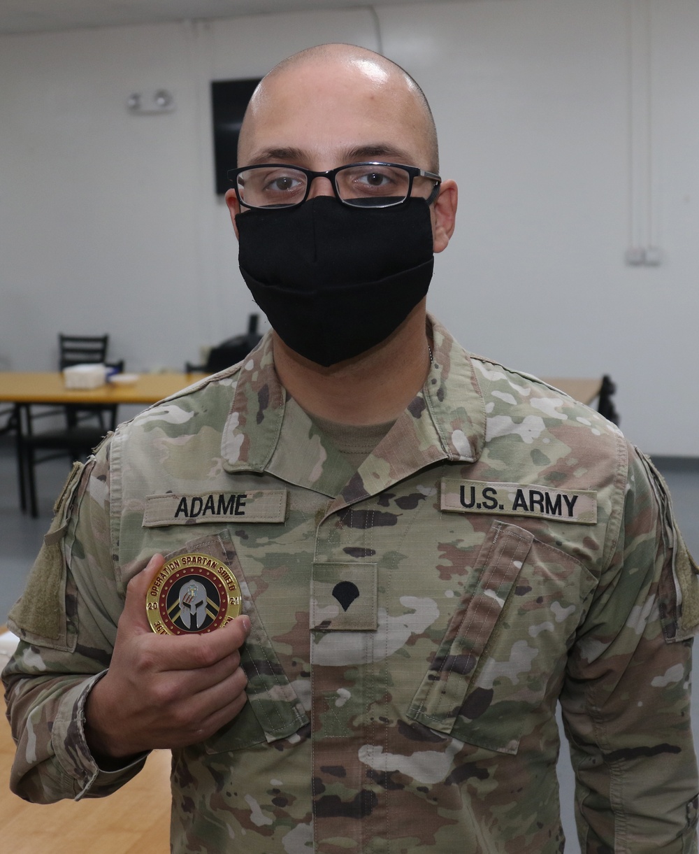 A Soldier from Bravo Battery, 5th Battalion, 52nd Artillery Regiment, receives Operations Spartan Shield coin from Task Force Spartan leadership