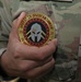 A Soldier from Bravo Battery, 5th Battalion, 52nd Artillery Regiment, receives Operations Spartan Shield coin from Task Force Spartan leadership