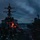 USS BARRY and JMSDF JS TOWADA Night Replenishment at Sea A U.S. Navy guided-missile destroyer is conducting an underway replenishment (UNREP) operation alongside a replenishment vessel at dusk or dawn. The two ships are connected by transfer lines visible between them, with crew members visible on the destroyer's deck managing the operation. The scene is captured in low-light conditions with overcast skies and illuminated by red and orange operational lights.