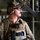 75th EAS moves cargo in East Africa A military service member in full tactical gear is positioned inside what appears to be a large military transport aircraft. The individual is wearing multicam/OCP camouflage uniform, tactical plate carrier, communications headset with boom microphone, and ballistic eyewear. The background reveals the interior structural elements of the aircraft including a staircase and cargo tie-down chains.