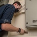 Sailor Prepares Bulkhead for Paint