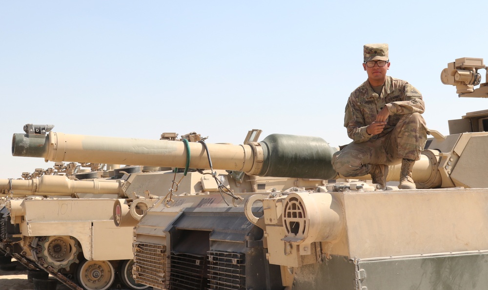 Spc. Isaiah Cabrera from Hemet, CA, a tank driver with 1st Battalion, 6th Infantry Regiment, 2nd Brigade Combat Team, 1st Armored Division, crouches on top of an M-1 Abrams tank