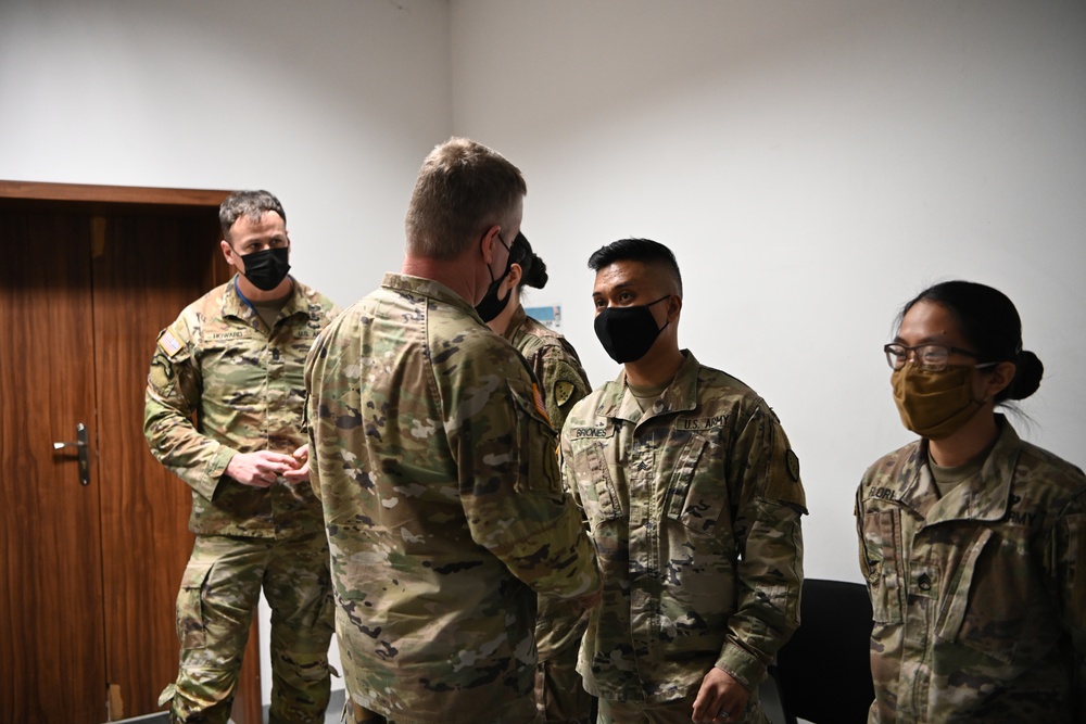 U.S. Army Maj. General Christopher Mohan presents his coin to Alaska Army National Guard Sergeant Randy Briones.