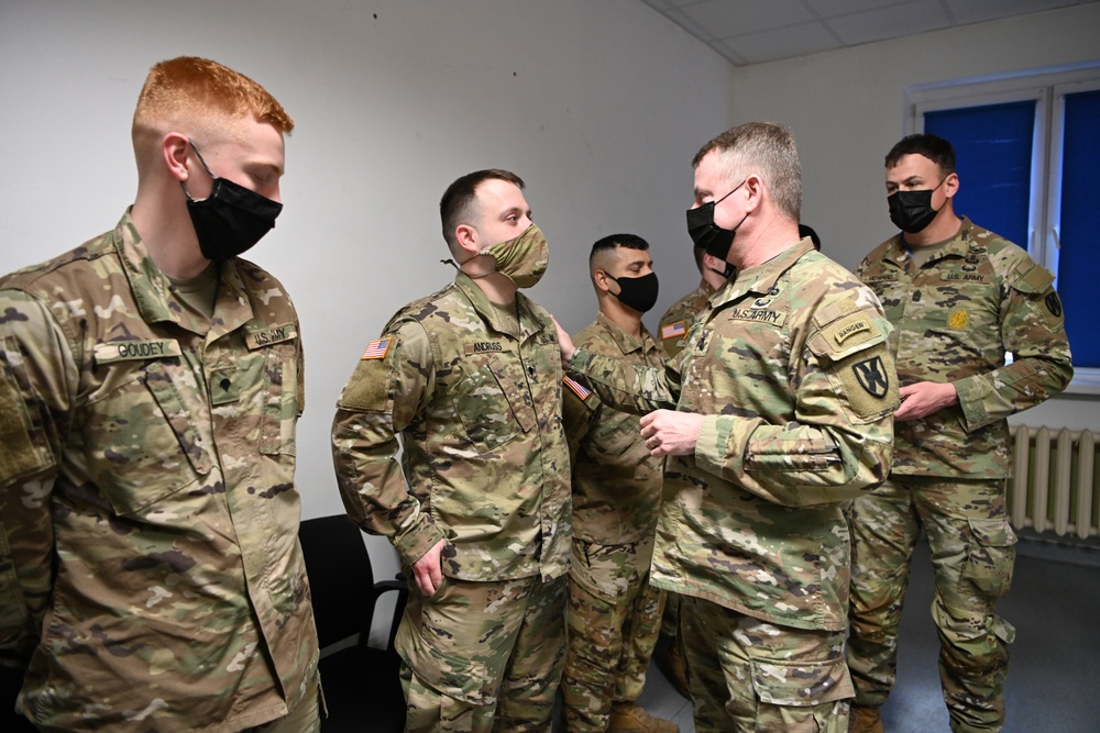 U.S. Army Maj. General Christopher Mohan presents his coin to Alaska Army National Guard Specialist Mikkel Andruss.