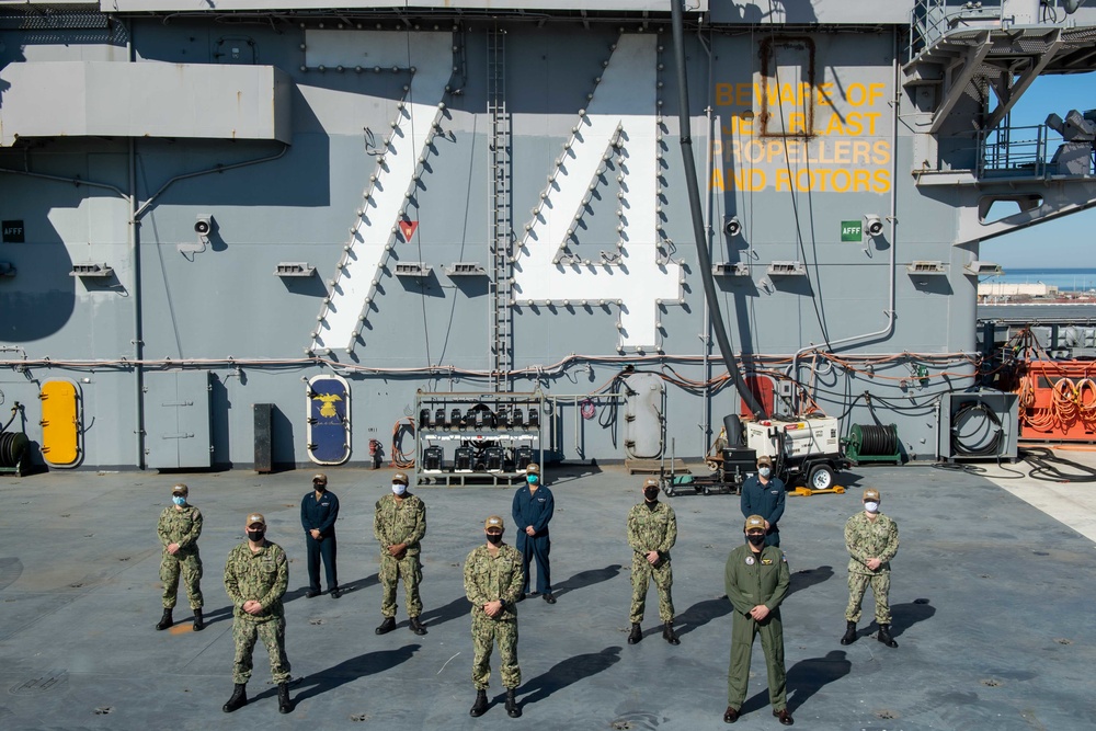 Sailors pose for a photo on the flight deck