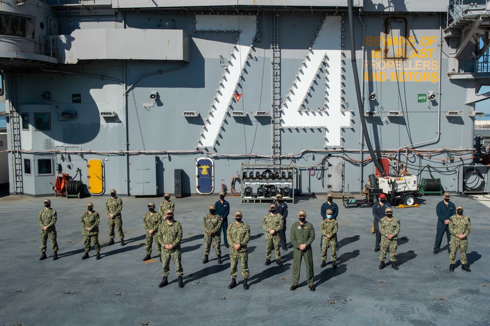 Sailors pose for a photo on the flight deck