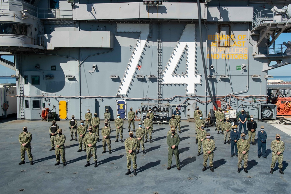 Sailors pose for a photo on the flight deck