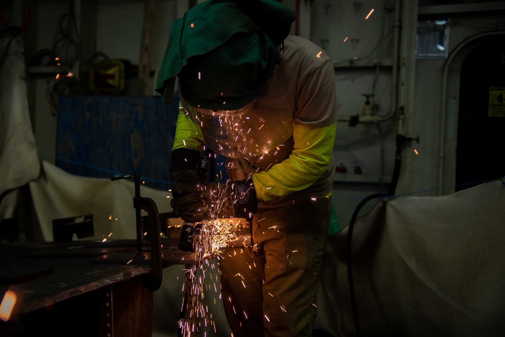 Contractor grinds metal in hangar bay