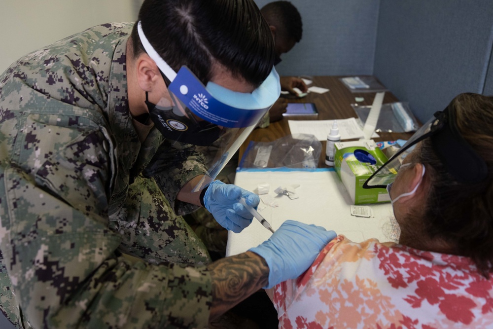 Service members inoculate community members on the opening day of the Jersey City, NJ CVC