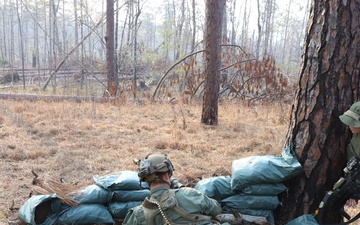 G-man crouched behind tree and sand bags await the 1st Brigade Combat Team, 82nd Air Borne Division