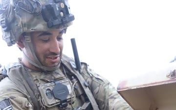 Soldier fills camel back with water from a water buffalo