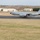 420th ABS supports Baltic Trident Exercise A U.S. Air Force KC-135 Stratotanker aircraft is landing or taking off on a runway at what appears to be a military airfield. The aircraft bears USAFE (United States Air Forces in Europe) markings on the tail fin along with a 'D' tail code. The surrounding environment includes military-style hangars and buildings consistent with a European air base, likely in the United Kingdom based on the landscape.