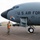 420th ABS supports Baltic Trident Exercise A U.S. Air Force aircraft, serial number 0036, is parked on a tarmac with a ground crew member in military uniform and orange safety vest standing beneath the nose. The aircraft bears the nose art 'Homesick Angel' and a unit insignia patch on its fuselage. The scene appears to be a pre-flight or post-flight ground operations scenario at a military airfield.