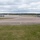 420th ABS supports Baltic Trident Exercise A military airfield apron and taxiway area showing multiple large military aircraft parked or taxiing on the tarmac. The scene appears to be a busy flight line with numerous aircraft spread across the ramp area under overcast skies. The setting is consistent with a US Air Force base, likely in the United Kingdom based on the landscape and vegetation.