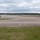 420th ABS supports Baltic Trident Exercise A wide-angle view of a military airfield tarmac showing multiple large military aircraft parked on the apron and taxiways. The aircraft appear to be US Air Force KC-135 Stratotanker aerial refueling aircraft in gray livery. The scene is set under overcast skies with green grass infields visible in the foreground.