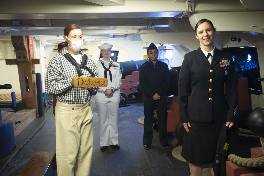 Sailors assigned to USS Constitution present a new gun name for the Navy’s first enlisted female Loretta Walsh during a Facebook live tour