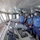 A group of naval officers in blue uniforms and face masks are gathered on the bridge/command deck of a naval vessel. They appear to be conducting an inspection, training exercise, or operational briefing around the ship's navigation and control console. The senior officer, distinguished by a white-topped cap and shoulder epaulettes, is prominently positioned at the front.