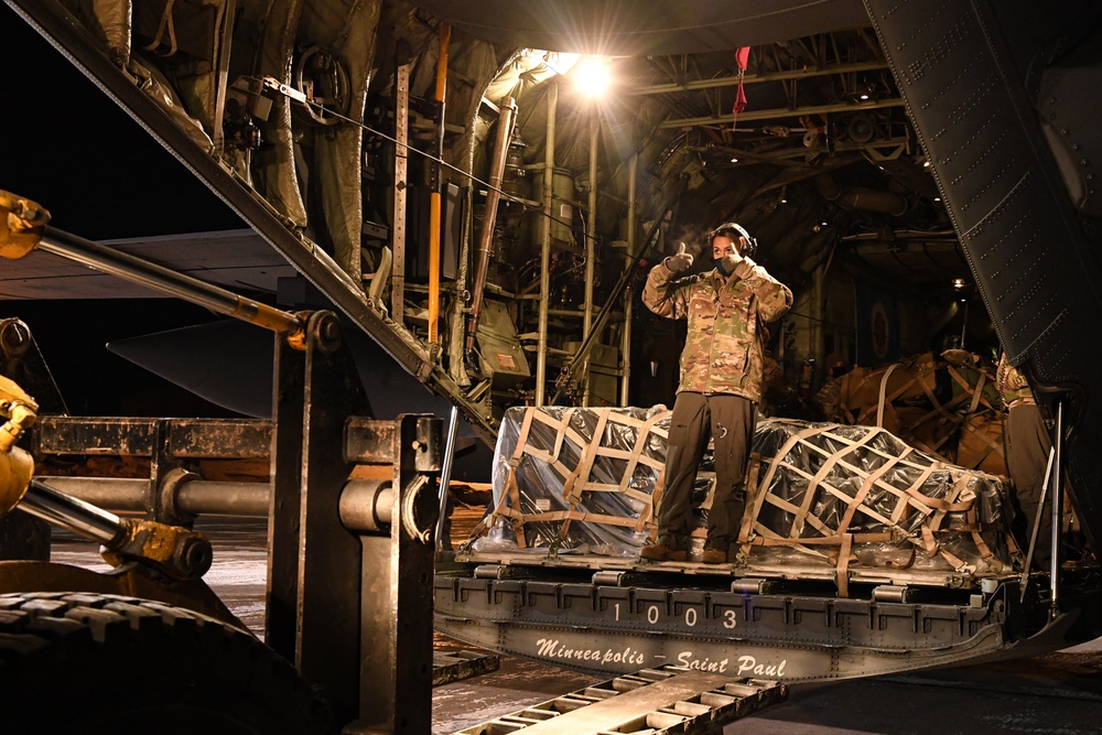 A U.S. Air Force loadmaster, directs a forklift into place in order to unload equipment from a C-130 Hercules