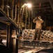 A U.S. Air Force loadmaster, directs a forklift into place in order to unload equipment from a C-130 Hercules