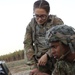 A Lieutenant over looking a shoulder of a Soldier in on a computer controlling the Raven system out in the field at JRTC