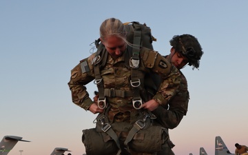 Soldier jump equipment being checked by a jumpmaster with planes in background