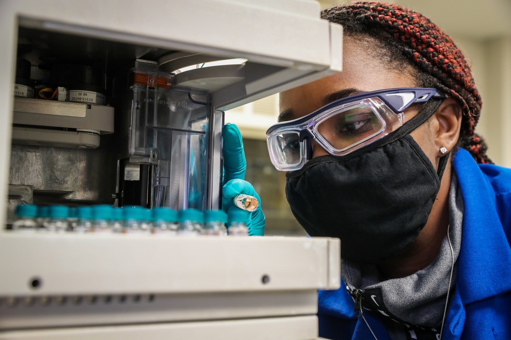 Scientist Keshia Capers places sample vial into an auto sampler tray for instrumental analysis