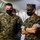 Marines with 3d Supply Battalion demonstrate their field communication capabilities Two U.S. Marines in the foreground stand inside a military tent wearing MARPAT digital camouflage uniforms and black face masks. Both have 'U.S. Marines' tape visible on their uniforms; the marine on the right has his arms crossed and is wearing a watch. Additional personnel in similar uniforms are visible in the background.