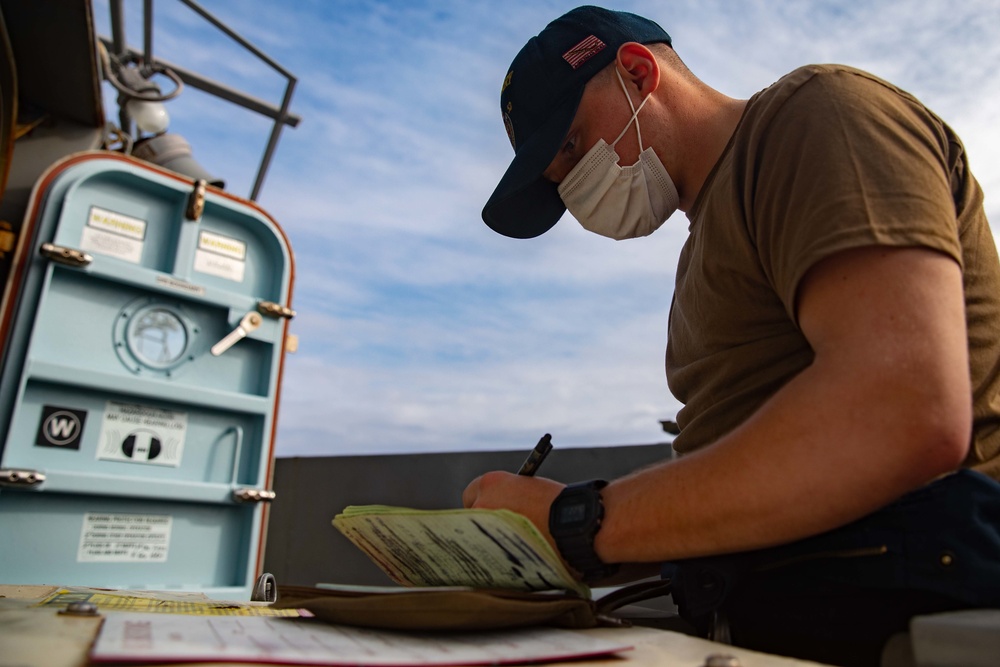 Gunners Mate Seaman Cameron Carter performs an hourly temperature check on USS Barry's stored ammunition