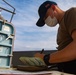 Gunners Mate Seaman Cameron Carter performs an hourly temperature check on USS Barry's stored ammunition