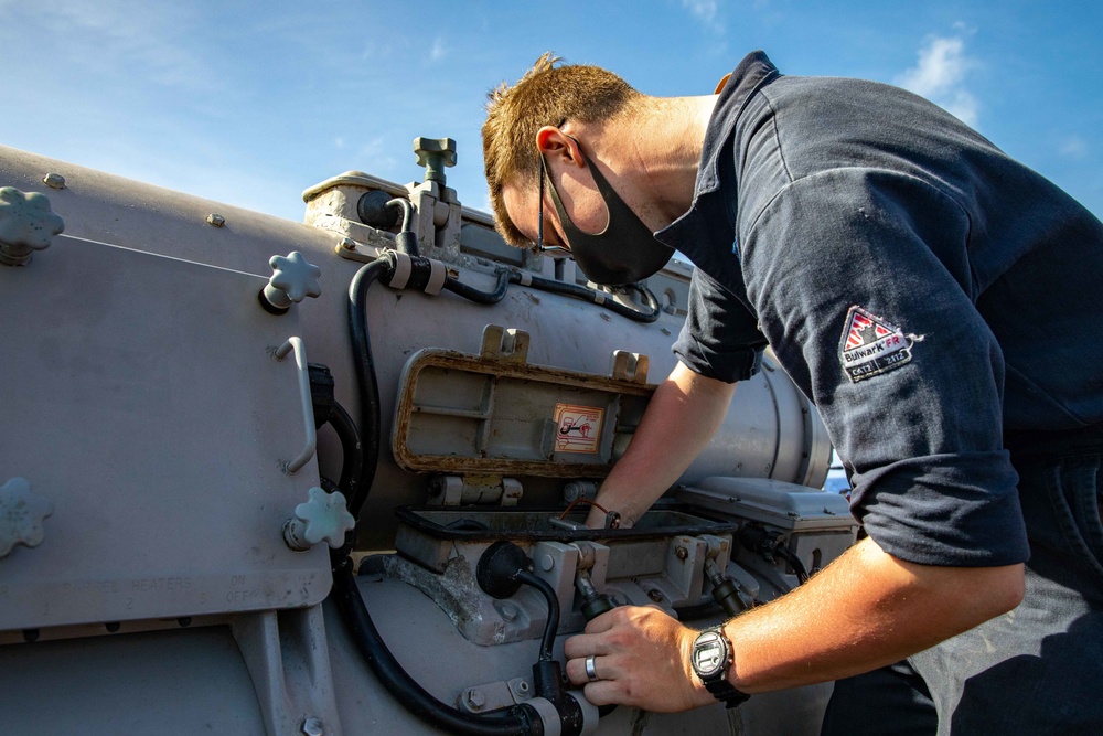 Gunners Mate Seaman John Rametta conducts maitenance on a torpedo launcher aboard USS Barry