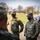 Several U.S. Army soldiers wearing OCP (Operational Camouflage Pattern) uniforms and black face masks are engaged in a conversation outdoors. Two soldiers are clearly identifiable by name tapes: 'MELSON' and 'BODEN', both bearing 'U.S. ARMY' tape. The setting appears to be a military installation or training area during late autumn or early spring.