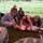 Joint Task Force-Bravo conducts overwater survival training A group of military personnel and civilians are conducting a first aid or combat casualty care training exercise outdoors under a canopy tent on a grassy field. A woman in athletic wear and a soldier in camouflage are performing CPR or trauma care techniques on a medical training mannequin. Several observers in military uniforms watch the demonstration closely.