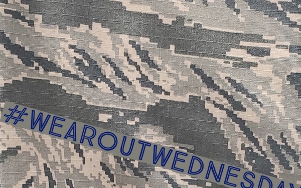 The image shows a close-up of a military digital camouflage fabric, consistent with the U.S. Air Force Airman Battle Uniform (ABU) pattern featuring gray, blue-gray, and tan pixel tones. Overlaid diagonally across the fabric is a semi-transparent banner with the hashtag '#WEAROUTWEDNESDAY' in blue text. This appears to be a social media promotional post related to wearing military uniforms or gear on Wednesdays.