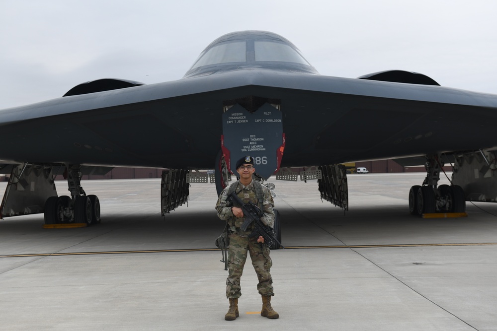 Security Forces Defender Airman 1st Class Elijah R. Posana stands in front of B-2 Spirit