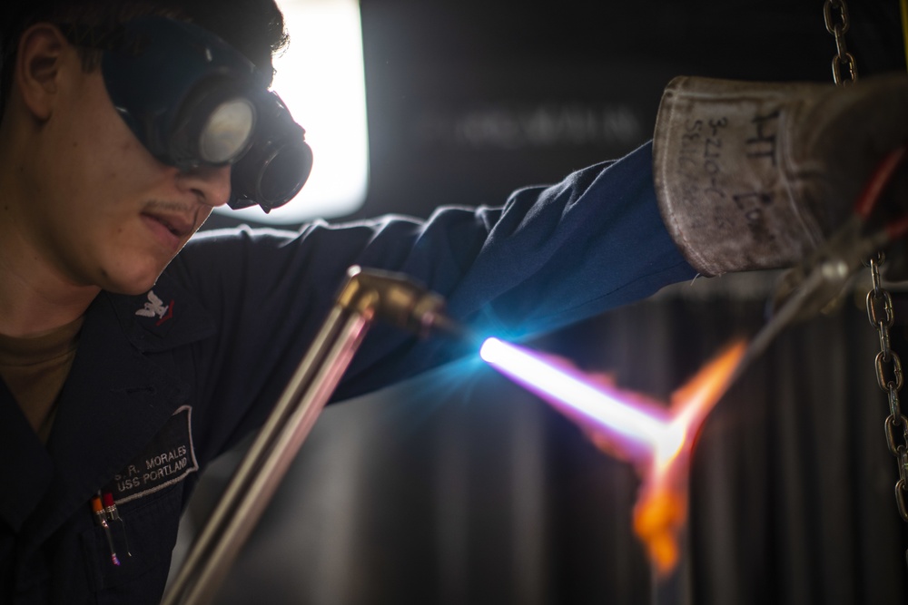 U.S. Navy HTFN 3rd Class welds oxygen tank brackets for USS Portland medical clinic