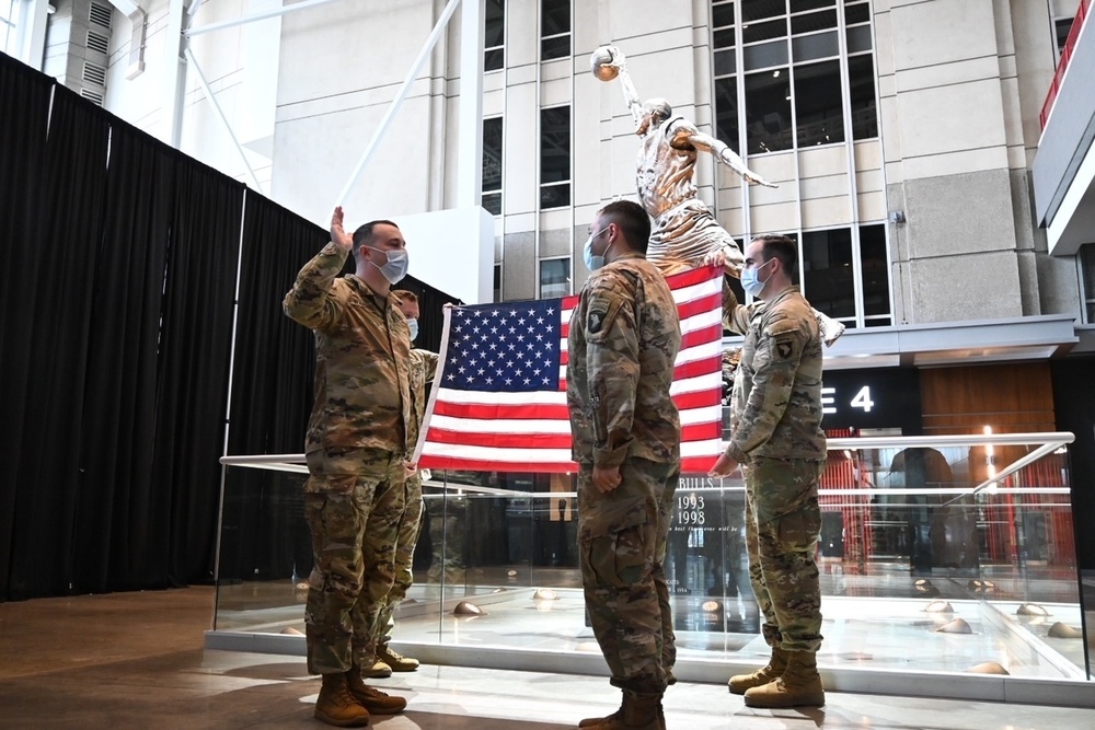 Staff Sgt. Chase Warren reenlists at the Michael Jordan statue at the United Center COVID-19 Community Vaccination Center, Chicago