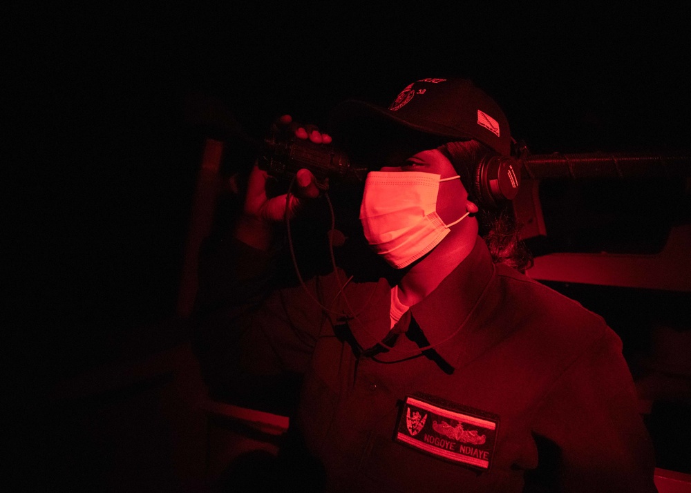 Seaman Nogoye Ndiaye scans for surface contacts on the bridge wing of USS Barry