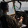 75th EAS Executes Tactical Airlift Mission in Manda Bay, Kenya A military aviator in multicam/OCP uniform is seated in the cockpit of a military transport aircraft, actively piloting the aircraft over what appears to be a body of water. The pilot is wearing Bose noise-canceling headphones and operating flight controls including a yoke and throttle. A heads-up display (HUD) or navigation mirror is visible in the upper center of the windscreen.